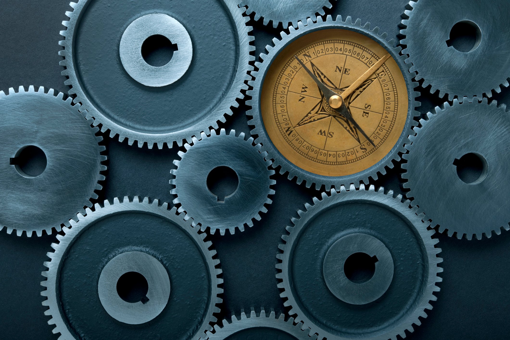 Strategic alignment and optimization concept: interlocking metal gears with a compass symbolizing direction and maximizing ROI in corporate language training